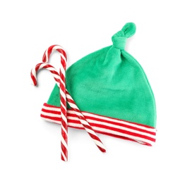 Photo of Cute small elf hat and candy canes on white background, top view. Christmas baby clothes