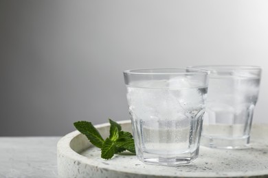 Photo of Glasses of soda water with ice and mint on grey table. Space for text