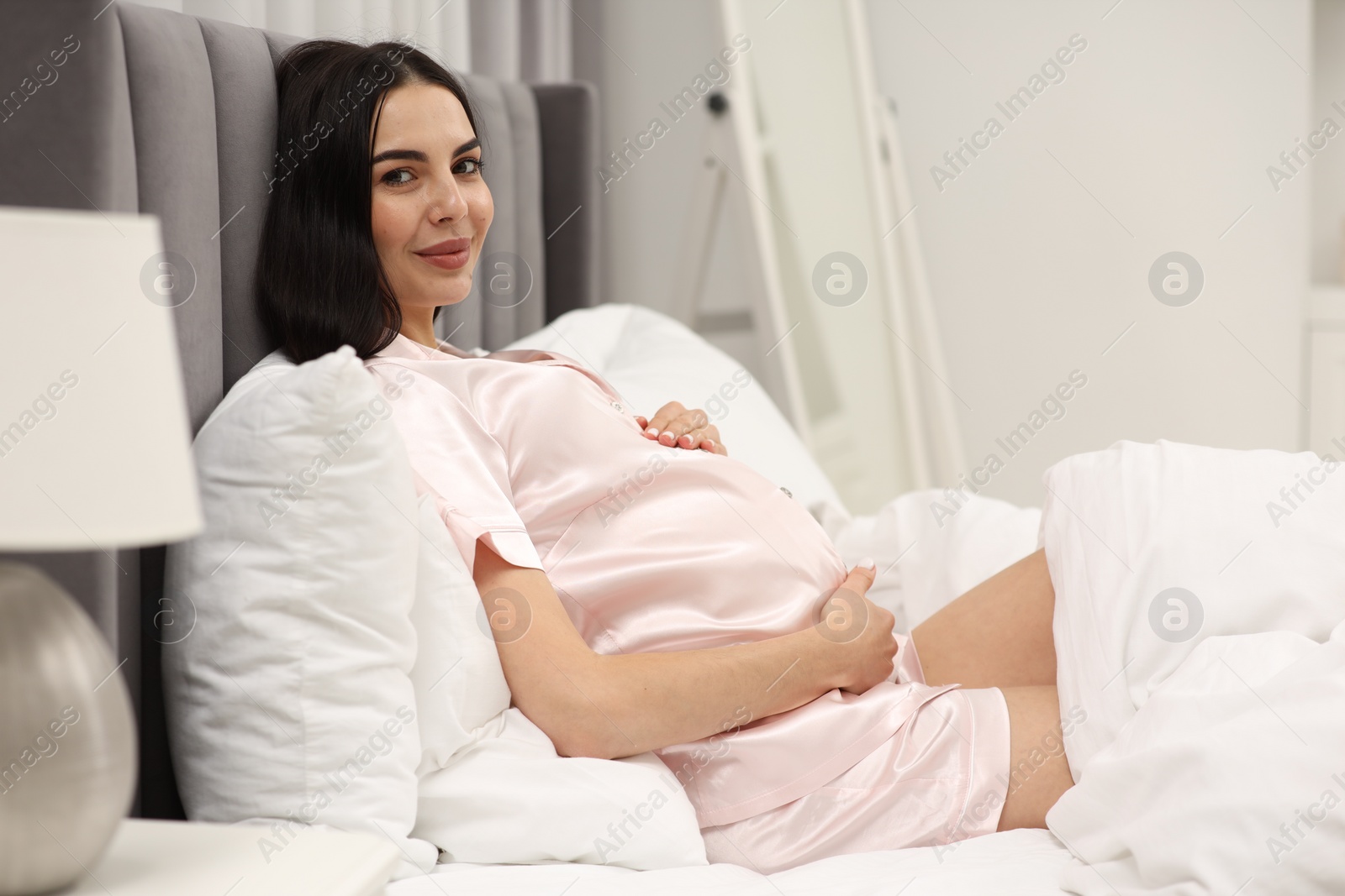 Photo of Pregnant young woman in bed at home