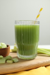 Glass of delicious celery juice and vegetables on wooden board