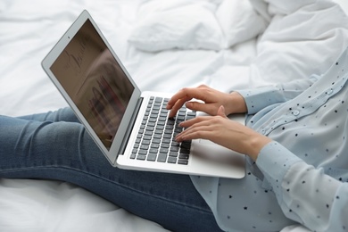 Photo of Woman holding laptop with open beauty blogger site on bed, closeup