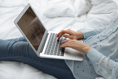 Woman holding laptop with open beauty blogger site on bed, closeup