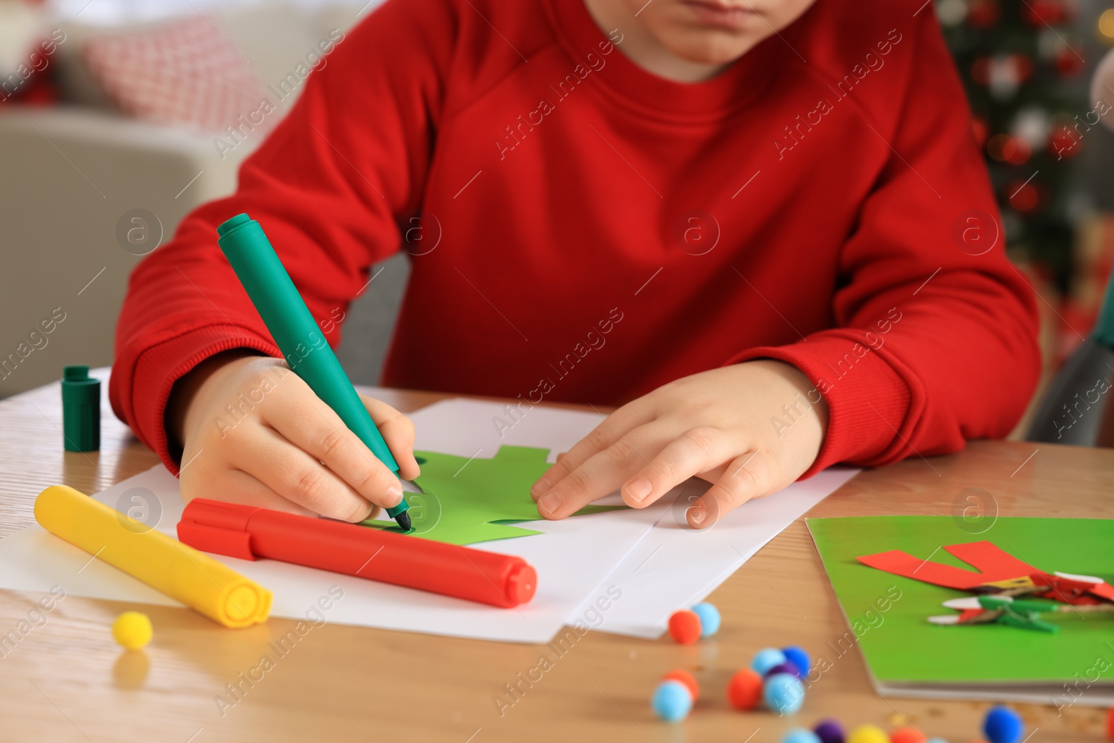 Photo of Little child making beautiful Christmas greeting card at home, closeup