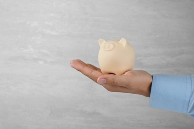 Photo of Man holding piggy bank on grey background, closeup view