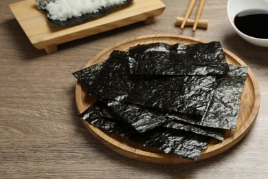 Photo of Plate with dry nori sheets on wooden table