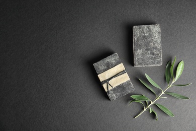 Handmade soap bars with olive twig and space for text on black background, top view