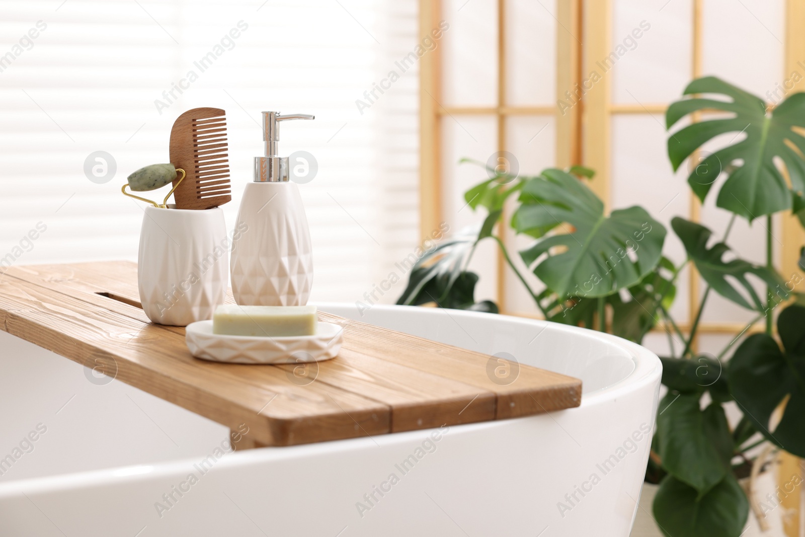 Photo of Different personal care products and accessories on bath tub in bathroom