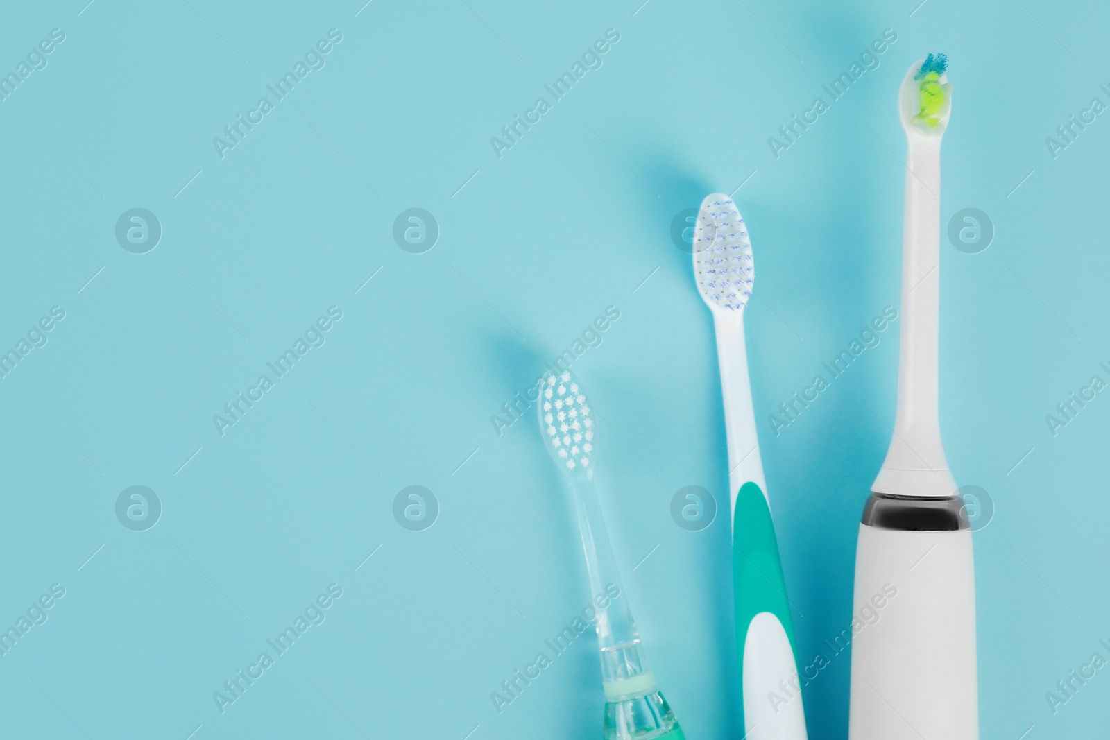 Photo of Electric toothbrushes on light blue background, flat lay, Space for text