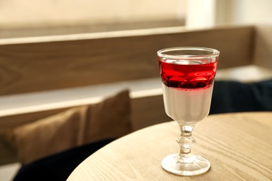 Photo of Delicious panna cotta dessert with berries on wooden table. Space for text