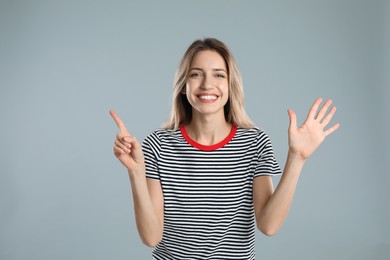 Photo of Woman showing number six with her hands on light grey background