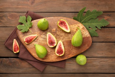 Photo of Cut and whole green figs on wooden table, flat lay