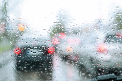 Blurred view of road through wet car window. Rainy weather