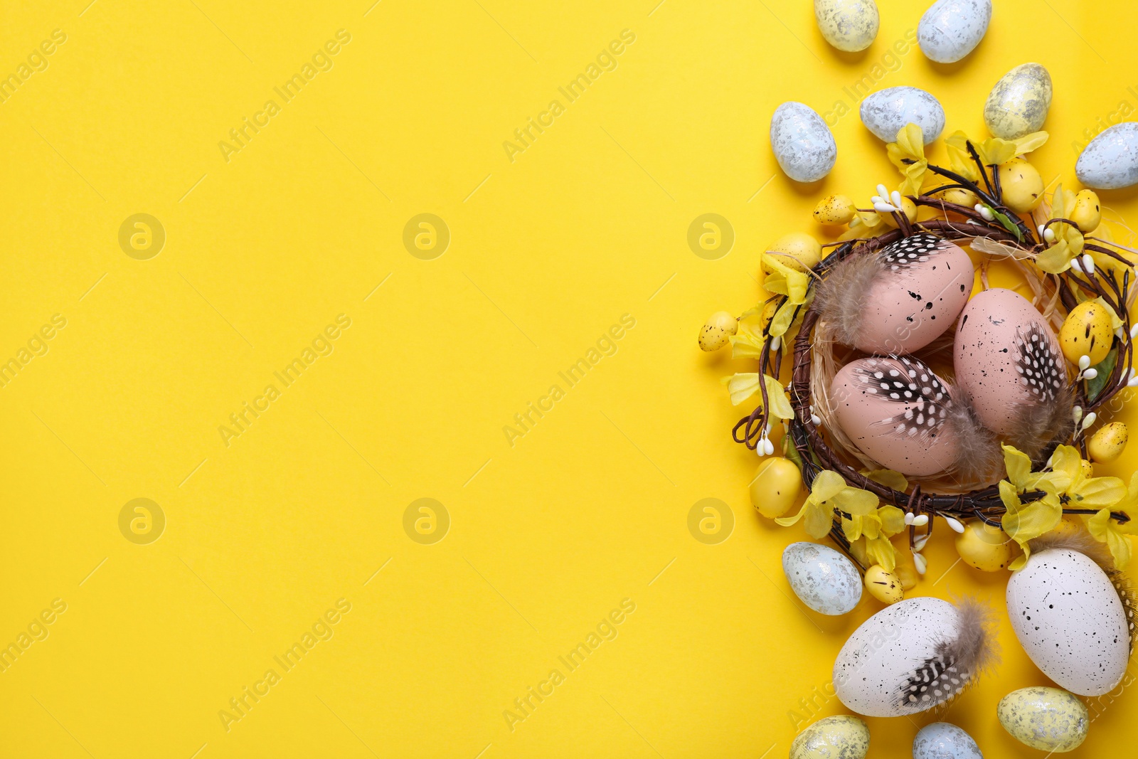 Photo of Decorative nest with many painted Easter eggs on yellow background, flat lay. Space for text