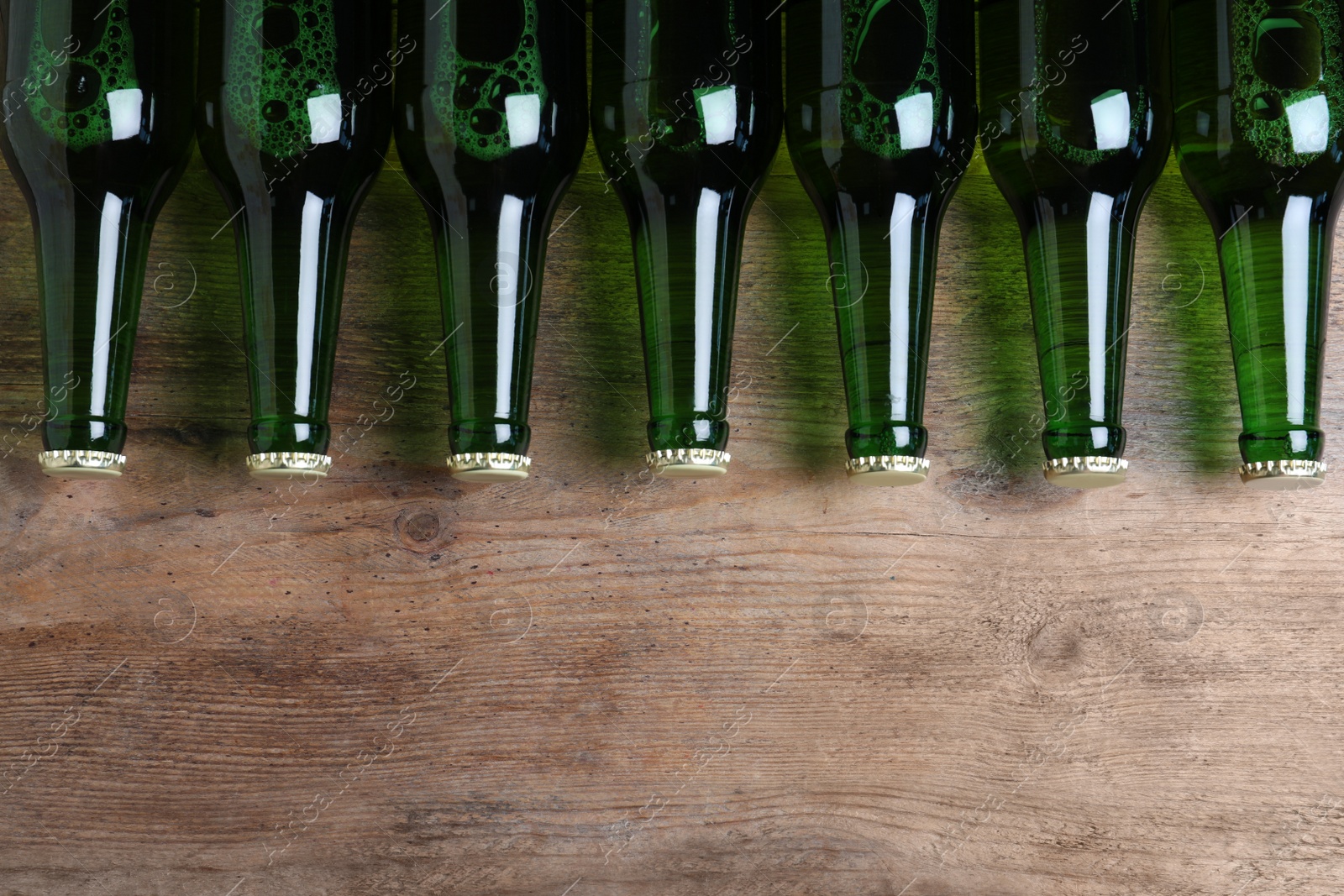 Photo of Bottles of beer on wooden table, flat lay. Space for text