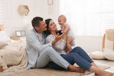 Photo of Happy family with their cute baby on floor in bedroom