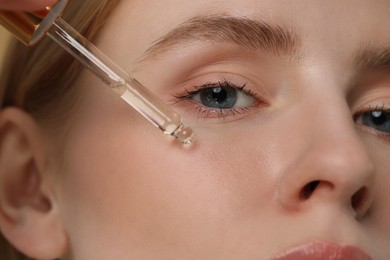 Woman applying essential oil onto face, closeup