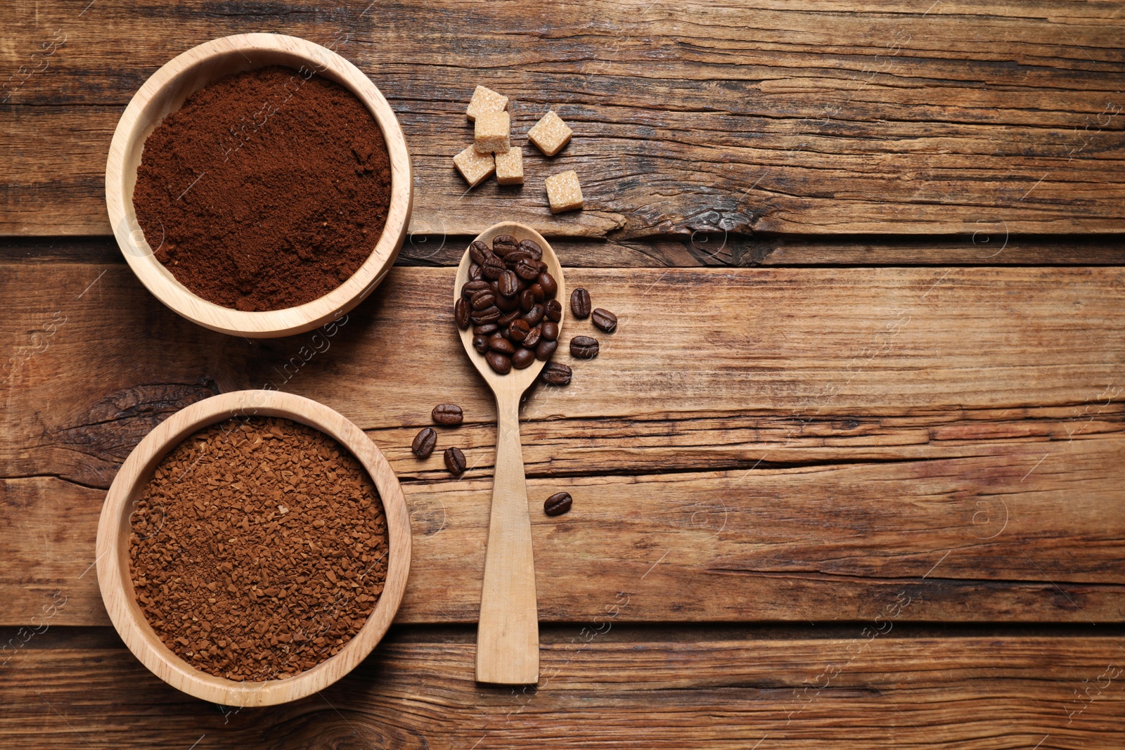 Photo of Instant and ground coffee, roasted beans and sugar on wooden table, flat lay. Space for text