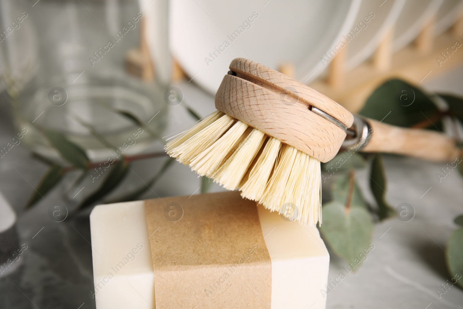 Photo of Cleaning brush and soap bar for dish washing on table, closeup