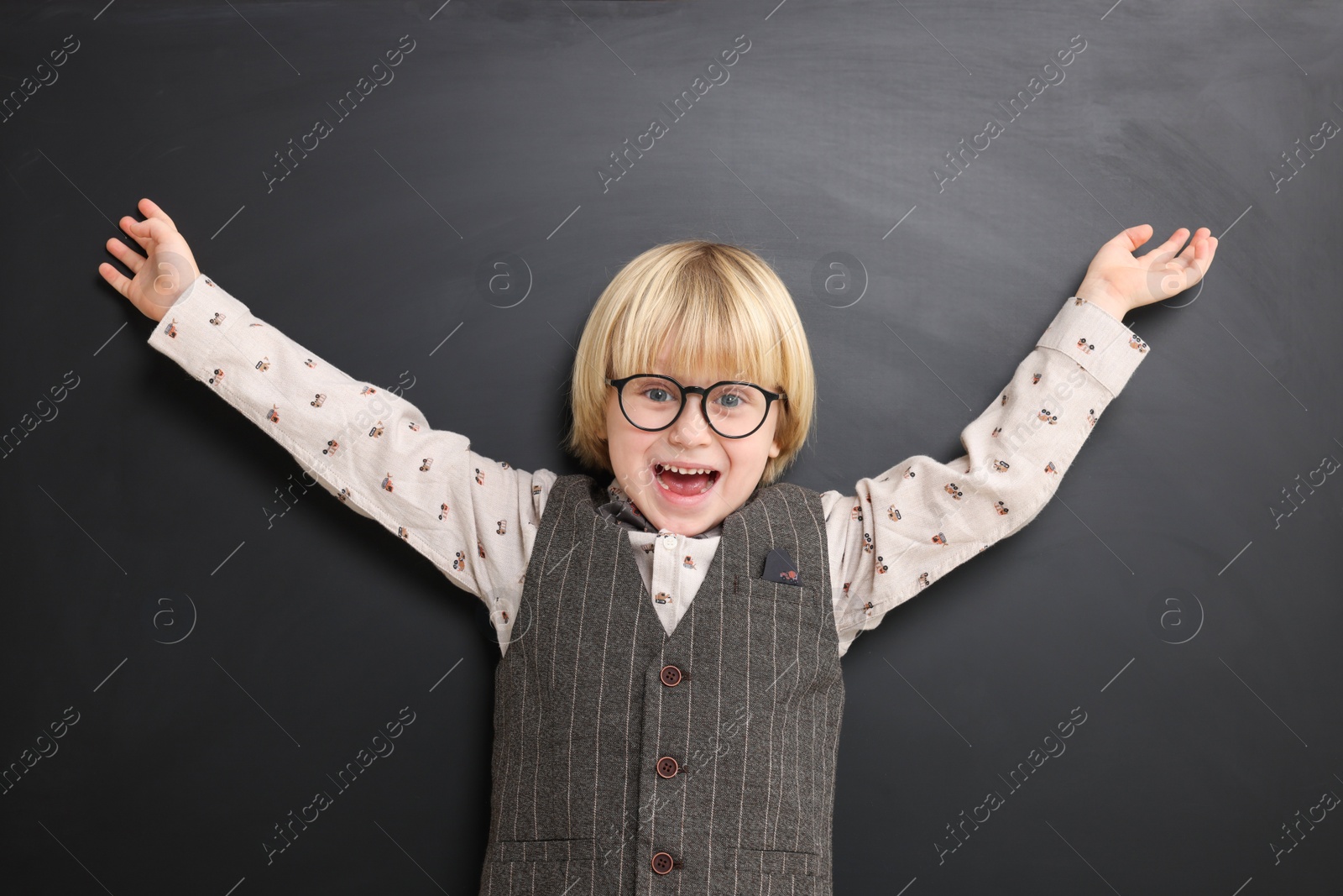 Photo of Emotional little school child in uniform near chalkboard