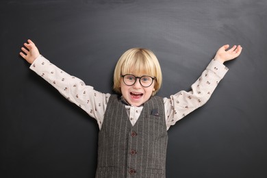 Emotional little school child in uniform near chalkboard