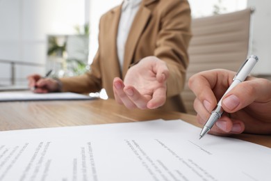 Photo of Businesspeople signing contract at table in office, closeup