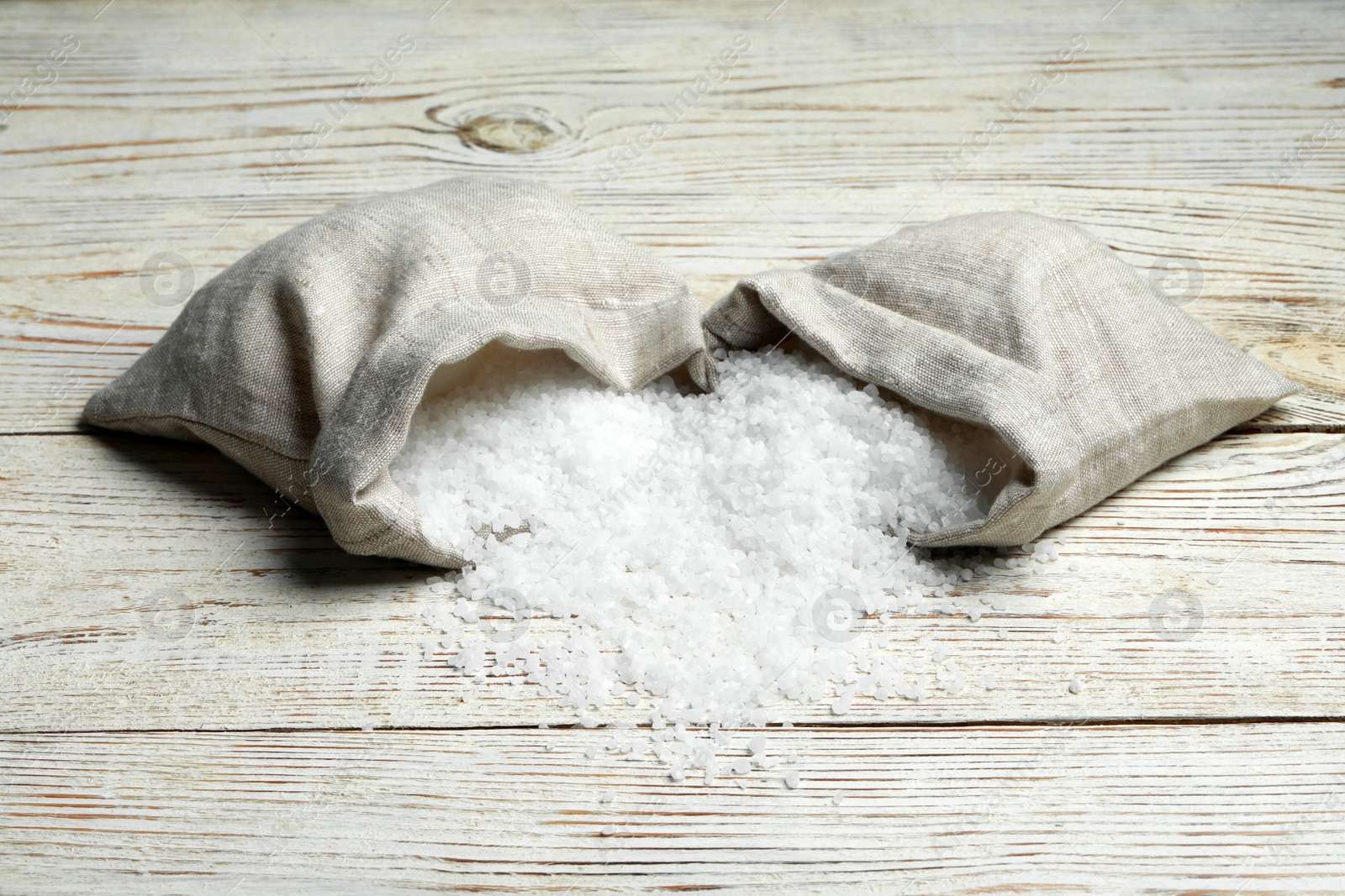 Photo of Bags with natural sea salt on white wooden table