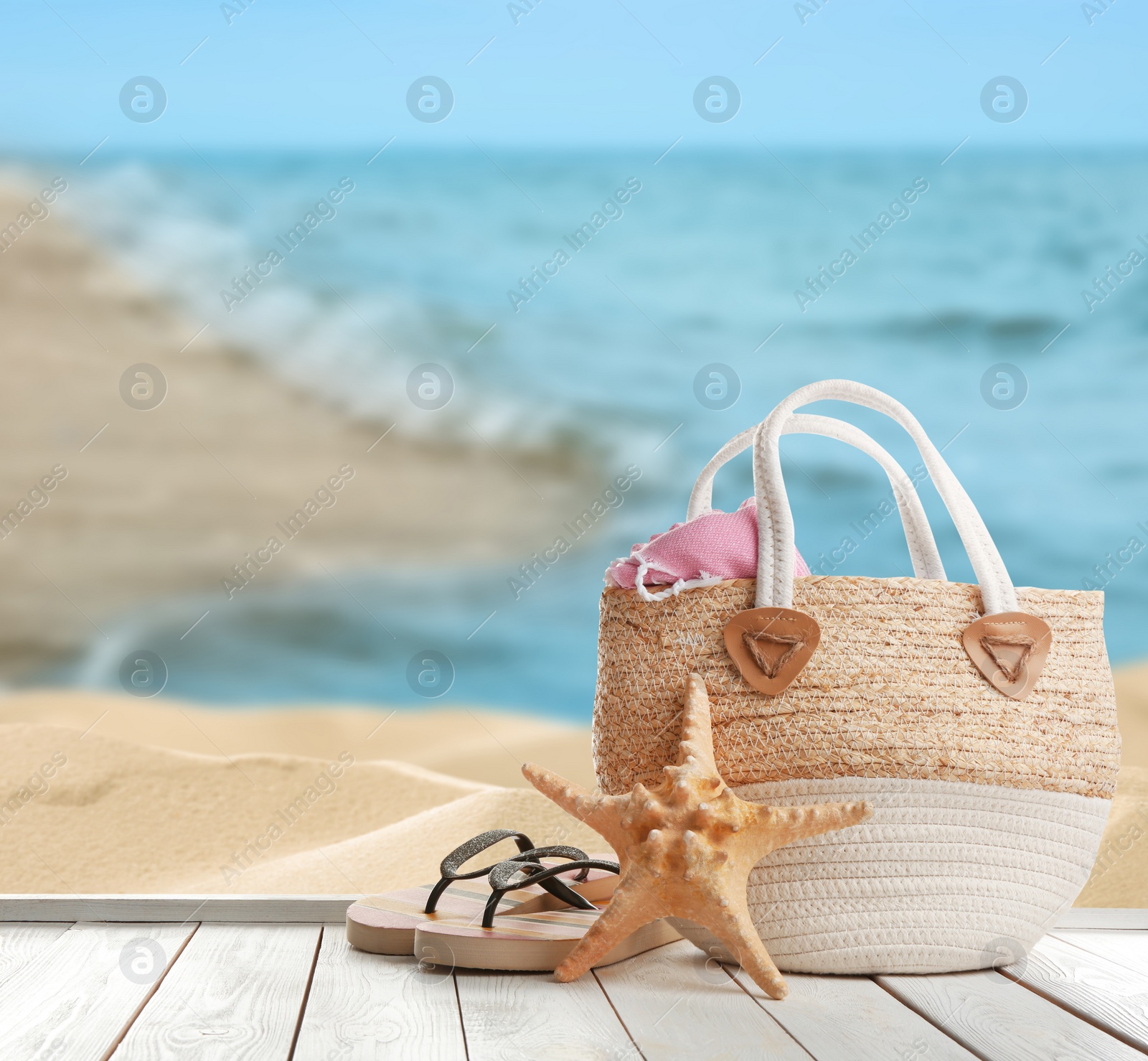 Image of Beach accessories on white wooden surface near ocean, space for text