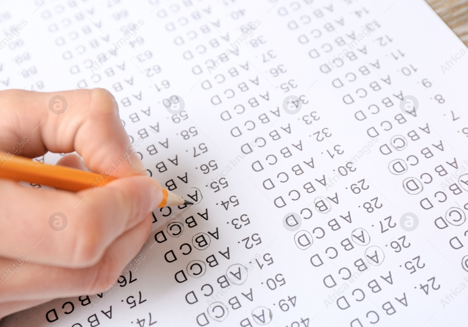 Photo of Student filling answer sheet at table, closeup