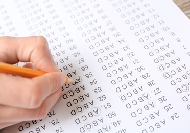 Photo of Student filling answer sheet at table, closeup