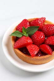 Photo of Tartlet with fresh strawberries on white table, closeup. Delicious dessert