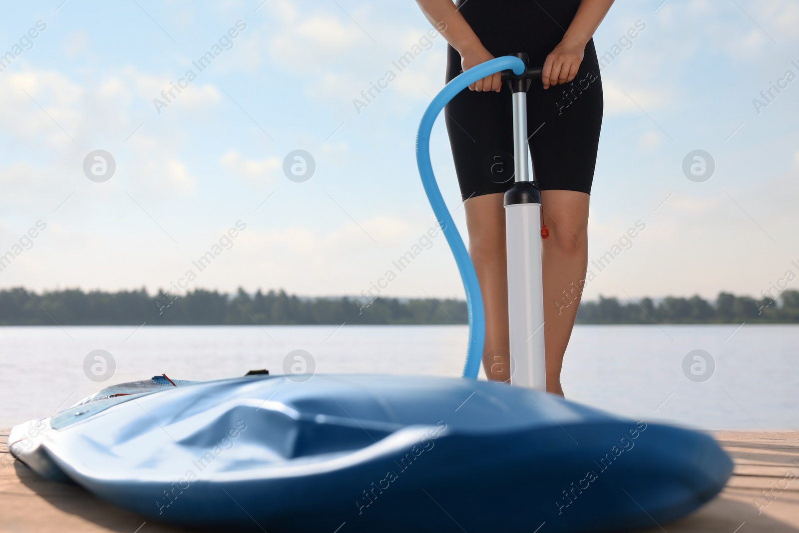 Photo of Woman pumping up SUP board on pier, closeup