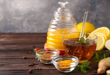 Photo of Tea with honey and ingredients on wooden table. Space for text