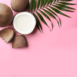 Photo of Fresh coconuts and palm leaf on pink background, flat lay. Space for text