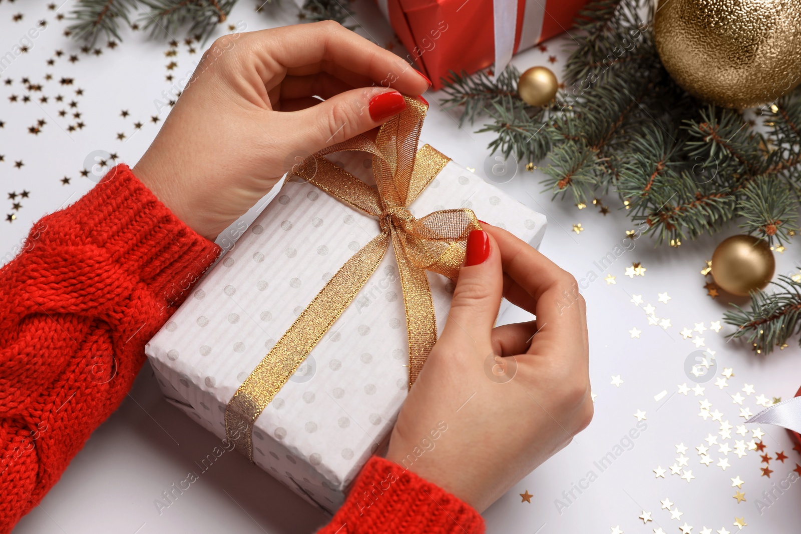 Photo of Woman with gift box near fir tree branches and Christmas decor on white background, closeup