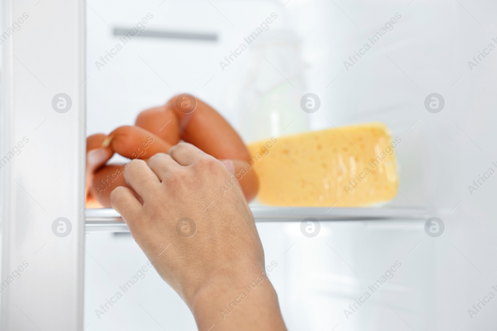 Photo of Young woman taking sausages out of refrigerator, closeup