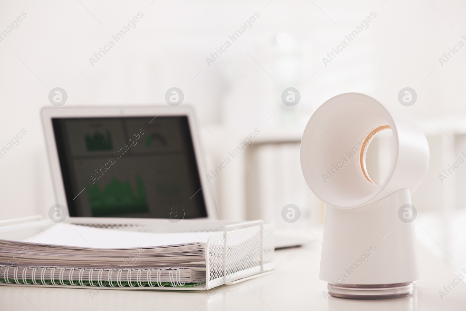 Photo of Modern electric fan on table in office. Space for text