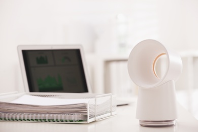 Modern electric fan on table in office. Space for text