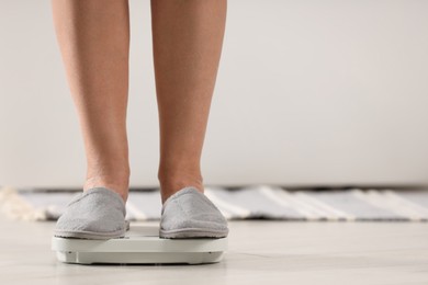 Photo of Menopause, weight gain. Woman standing on floor scales indoors, closeup. Space for text