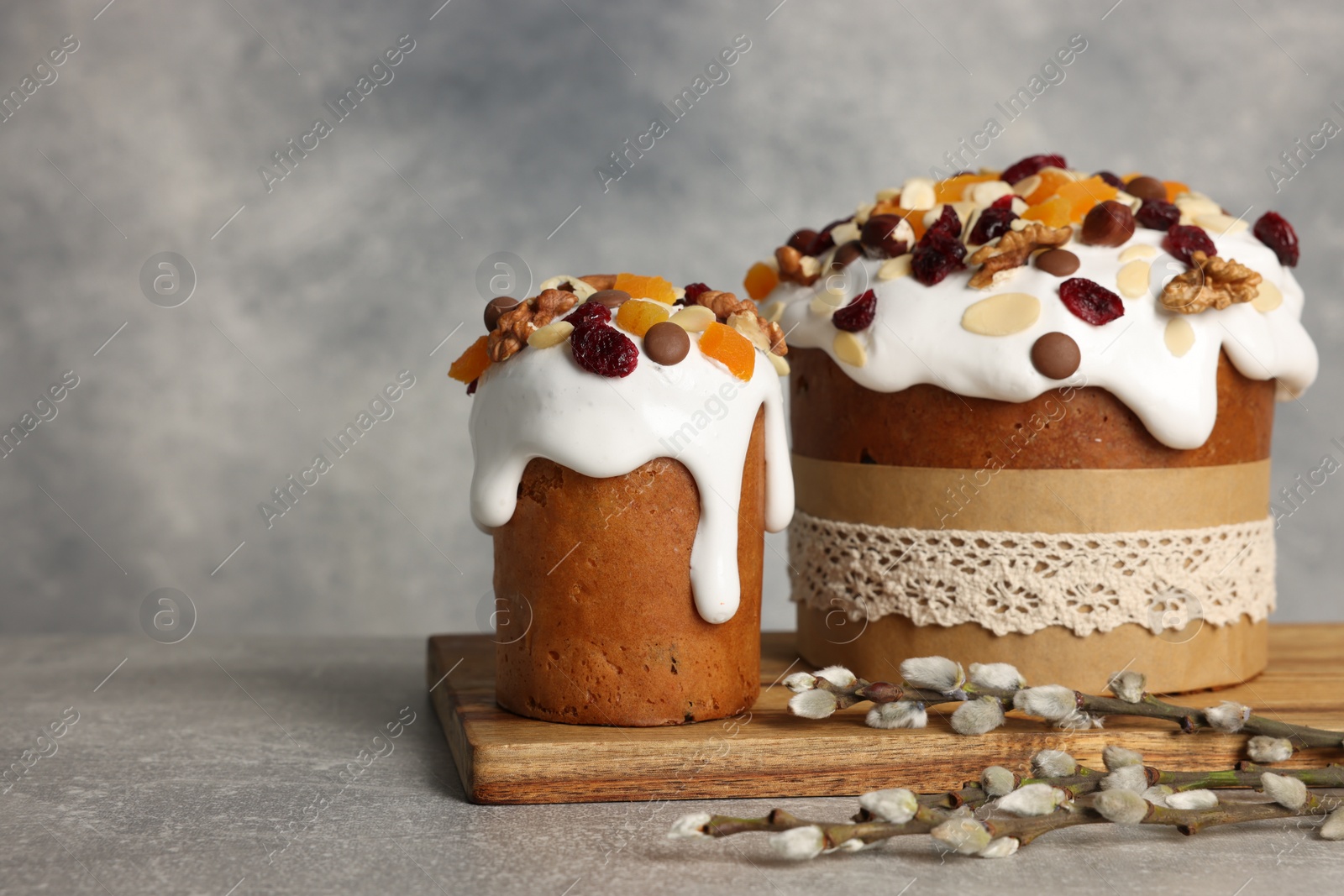 Photo of Tasty Easter cakes and willow branches on grey table. Space for text