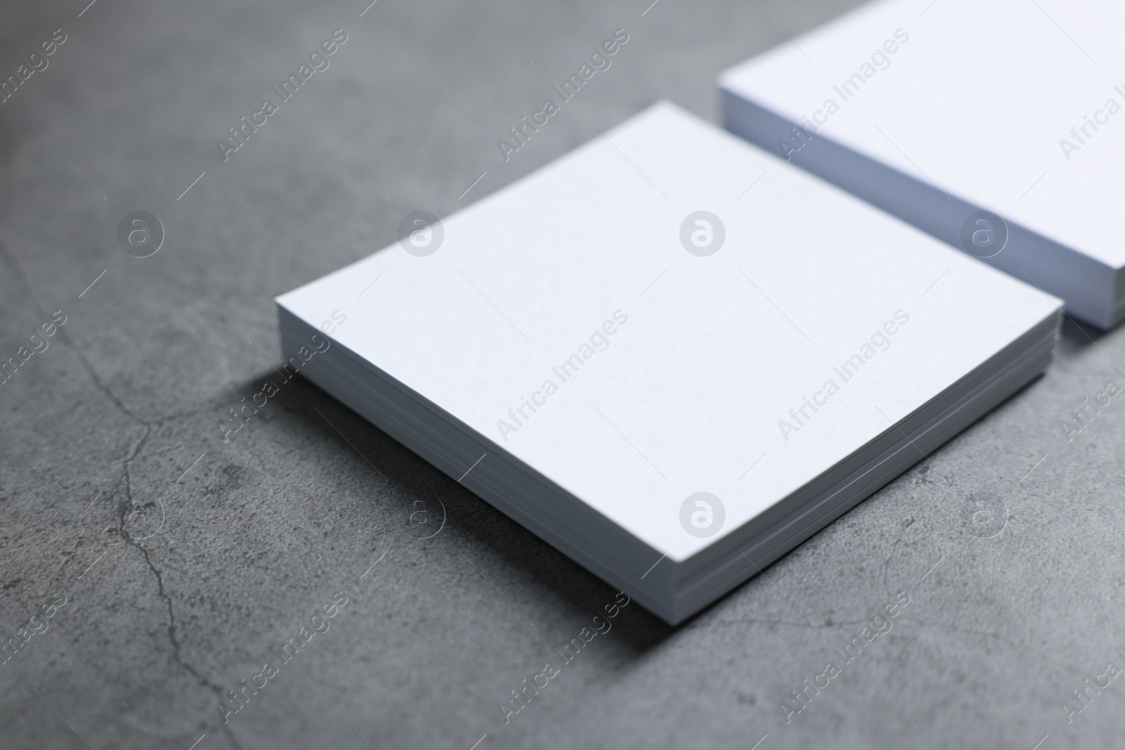 Photo of Blank paper sheets on grey textured table, closeup. Mockup for design