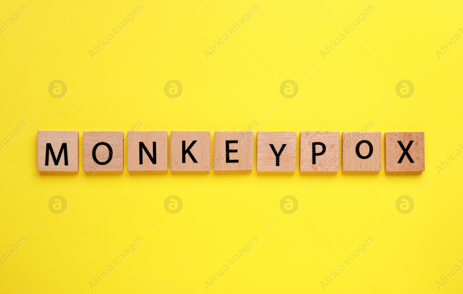 Photo of Word Monkeypox made of wooden cubes on yellow background, top view