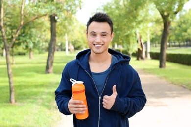 Man with bottle of protein shake in green park