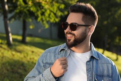 Photo of Handsome smiling man wearing sunglasses in park, space for text