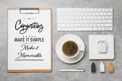 Image of Paper with phrase Copywriting Make It Simple Make It Memorable, keyboard and coffee on grey textured table, flat lay