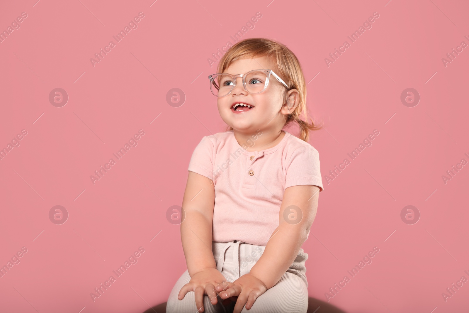 Photo of Cute little girl in glasses on pink background. Space for text