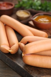 Photo of Many fresh delicious sausages on wooden table, closeup