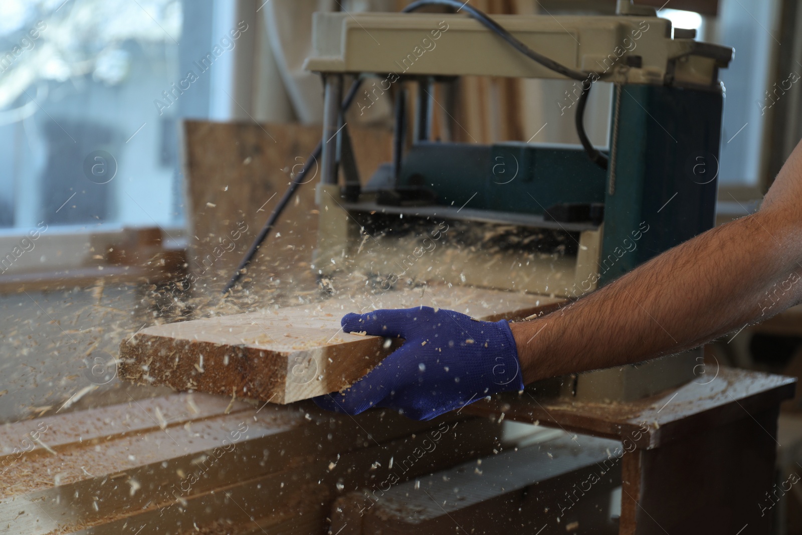 Photo of Professional carpenter working with grinding machine in shop, closeup