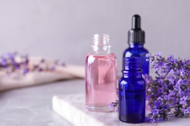 Photo of Bottles of lavender essential oil on marble table. Space for text