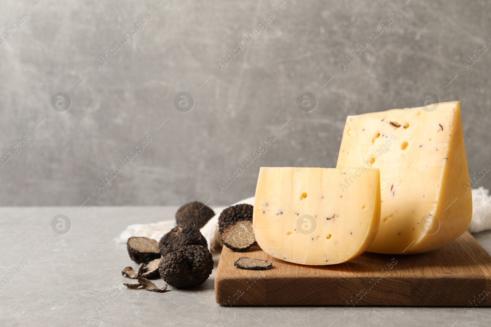 Photo of Delicious cheese and fresh black truffles on grey table. Space for text