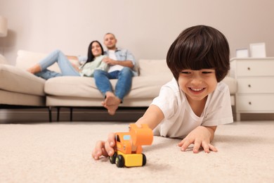 Photo of Child playing with toy and parents working at home